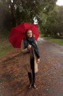 Mujer joven de pie con paraguas en el parque - foto de stock