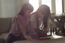 Siblings using digital tablet in living room at home — Stock Photo