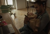 Padre sosteniendo a su bebé en la sala de estar en casa - foto de stock