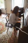 Hermosa vlogger femenina tocando el piano en casa - foto de stock