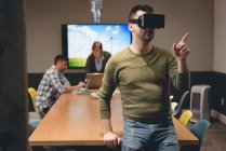 Hombre de negocios con auriculares de realidad virtual en la sala de reuniones en la oficina - foto de stock