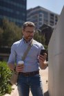 Людина використовує мобільний телефон, маючи каву в сонячний день — стокове фото