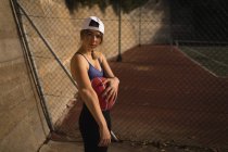 Portrait de femme tenant le basket sur le terrain de basket — Photo de stock