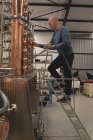 Travailleur masculin vérifiant la machine de distillerie dans l'usine — Photo de stock