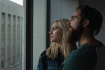 Thoughtful couple looking through window at home — Stock Photo