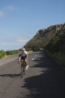 Байкер верхом на горном велосипеде по дороге в солнечный день — стоковое фото