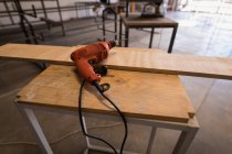 Bohrmaschine und Holzstück auf Tisch in Werkstatt. — Stockfoto