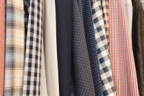 Gros plan de différentes chemises suspendues dans des cintres à la maison — Photo de stock