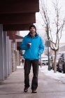 Homem andando enquanto toma café na calçada durante o inverno . — Fotografia de Stock
