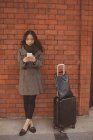 Жінка використовує мобільний телефон проти цегляної стіни на залізничній платформі — стокове фото