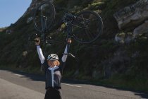 Aufgeregte Radfahrerin trägt Mountainbike auf Straße — Stockfoto