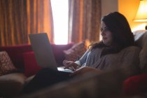 Крупним планом жіночий відеоблогер сидить на дивані під час використання ноутбука — стокове фото