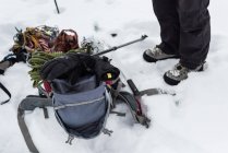 Baixa seção de caminhante de pé com mochila e equipamentos na região nevada — Fotografia de Stock