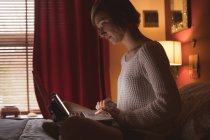 Женщина использует ноутбук на кровати в спальне дома — стоковое фото