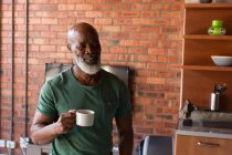Homme âgé souriant prenant un café à la maison — Photo de stock