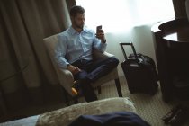 Empresário usando telefone celular no quarto de hotel — Fotografia de Stock