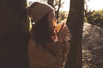 Mujer tomando café en el bosque - foto de stock
