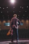 Mann steht mit Gitarre auf Theaterbühne. — Stockfoto