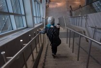 Woman moving down through staircase at station — Stock Photo