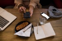 Frau benutzt Taschenrechner in Restaurant. — Stockfoto