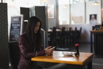 Молода жінка використовує мобільний телефон в ресторані — стокове фото