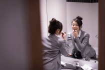 Бізнес-леді наносить помаду перед дзеркалом у ванній — стокове фото