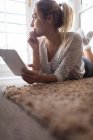 Жінка використовує цифровий планшет, лежачи на підлозі вдома — стокове фото