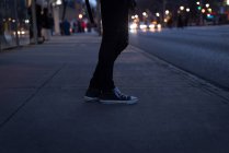 Low section of woman standing in city street at dusk — Stock Photo