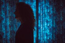 Smiling woman standing in dark room at home — Stock Photo