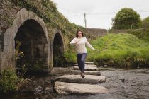 Frau läuft auf Steinweg in Fluss — Stockfoto
