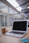 Laptop e copo descartável em uma mesa no escritório — Fotografia de Stock
