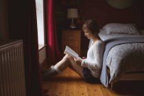 Schöne Frau liest Buch im Schlafzimmer zu Hause — Stockfoto