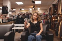 Красивая девушка делает селфи с мобильным телефоном на диване в торговом центре — стоковое фото