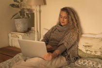 Ältere Frau benutzt Laptop im Schlafzimmer zu Hause — Stockfoto