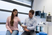 Physiotherapeut überprüft Blutdruck der Frau in Klinik — Stockfoto