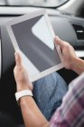 Gros plan des mains masculines à l'aide d'une tablette numérique dans la voiture — Photo de stock