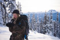 Femme en vêtements d'hiver examen photo sur appareil photo numérique par une journée ensoleillée — Photo de stock