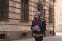 Молода жінка дивиться на мапу під час ходьби на вулиці — стокове фото