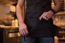 Mittlerer Teil des männlichen Kellners trägt schwarze Schürze im Café. — Stockfoto