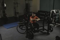 Homem deficiente sentado e olhando para barbell no ginásio — Fotografia de Stock