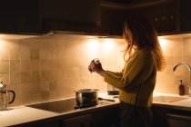 Woman preparing milk in kitchen at home — Stock Photo