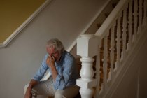 Беспокойный пожилой человек сидит дома на лестнице — стоковое фото