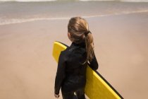 Fille réfléchie debout avec planche de surf sur la plage — Photo de stock