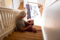 Hombre mayor usando el teléfono móvil en las escaleras en casa — Stock Photo