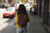 Вид ззаду дівчини-підлітка, що стоїть з рюкзаком у місті — стокове фото