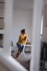 Nachdenkliche Frau sitzt zu Hause auf Stuhl — Stockfoto