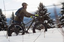 Mann läuft im Winter mit Fahrrad in verschneiter Landschaft. — Stockfoto