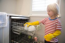 Хлопчик організовує посуд на кухонному візку вдома — стокове фото