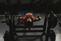 Інвалідний чоловік робить тренування грудей на лавці прес з барбелом в спортзалі — стокове фото