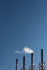 Дим, що виходить з заводського димоходу на прозоре небо — стокове фото